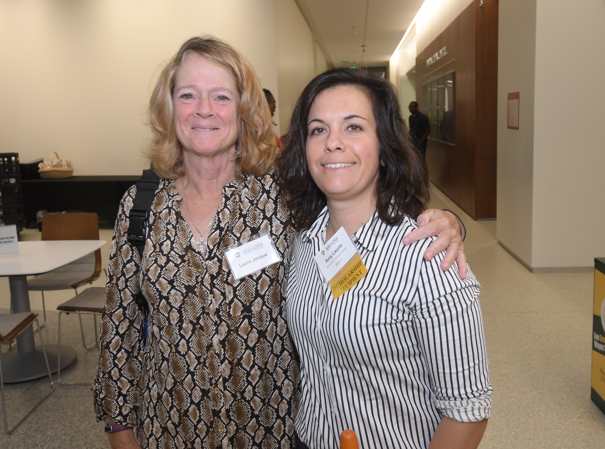 Laura Jocque and Amy Laurin smile with their arms around each other while at an Ilitch School scholarship event