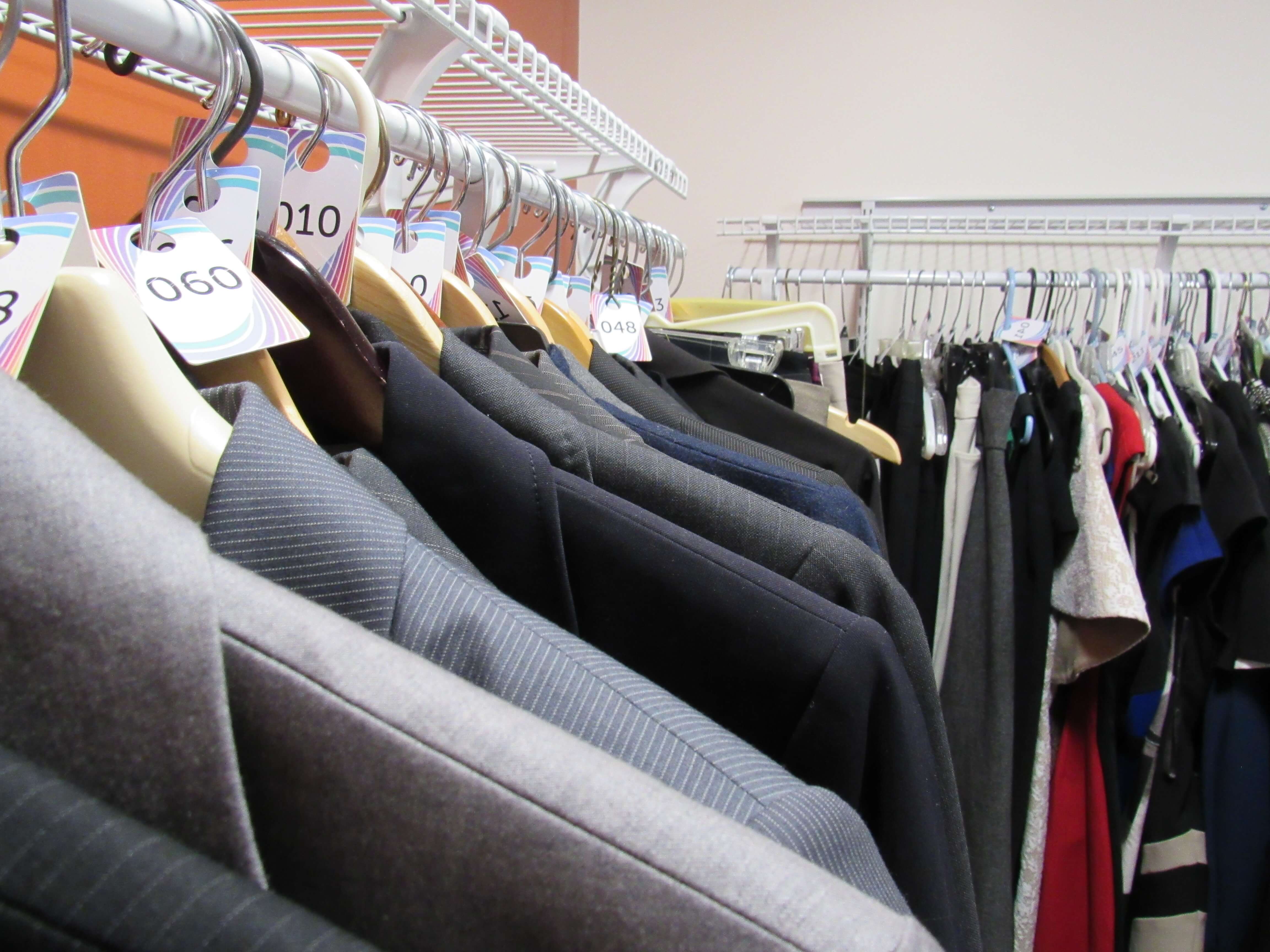 Suit jackets on hangers and other professional clothes on a rack in the Ilitch School dress closet 